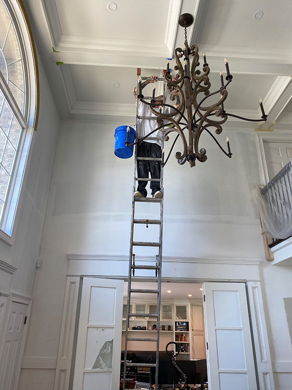 man in ladder painting ceiling
